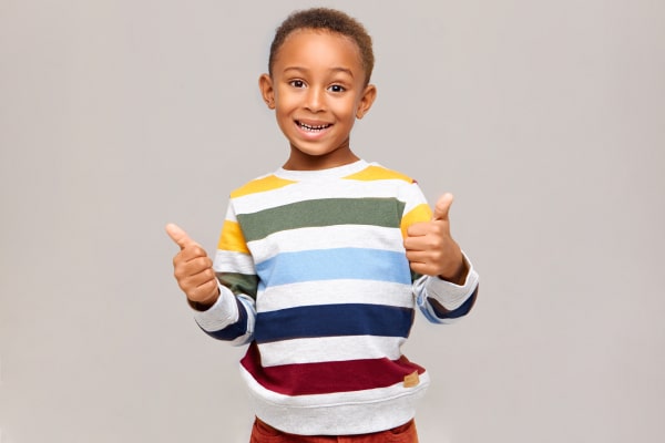 Routine Cleanings A boy standing raising his thumbs up